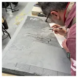 Romain Hugault dessinant sa pierre à l'atelier.